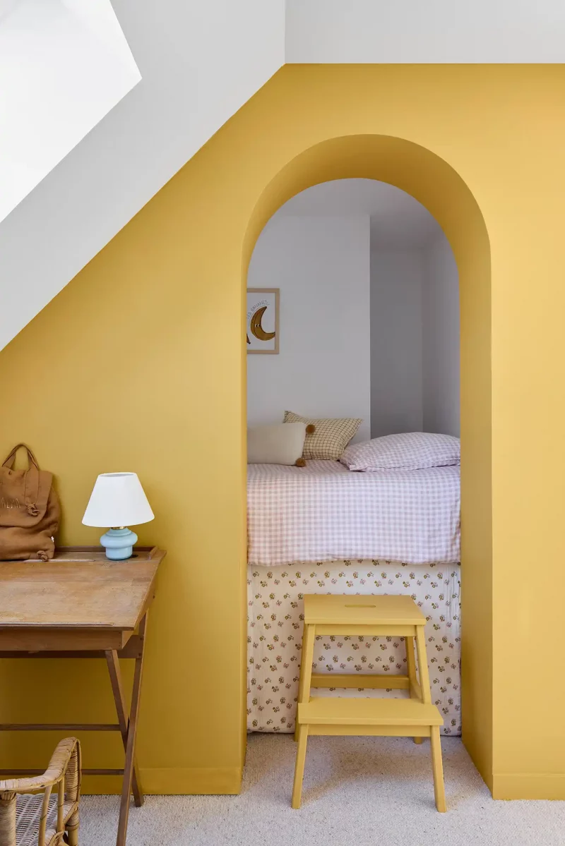 Alcôve de lit peinte en jaune avec arche minimaliste dans une chambre rénovée à Batz-sur-Mer.