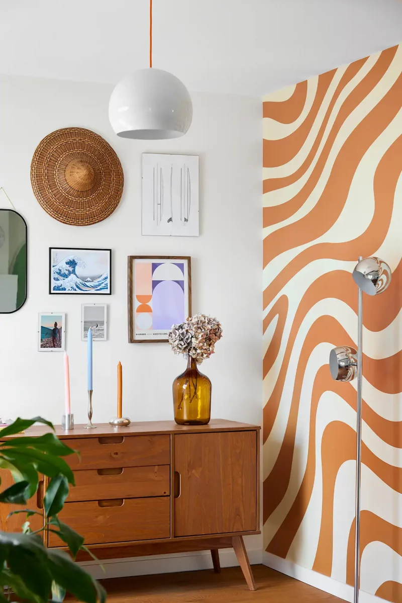 Détail de la décoration murale du salon avec un papier peint graphique orange et bois chaleureux.