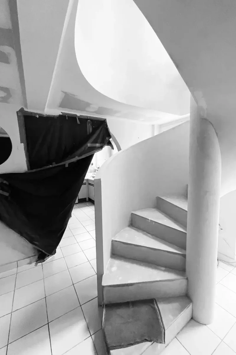 Escalier en colimaçon brut en plâtre et béton en cours de finition sur un chantier.