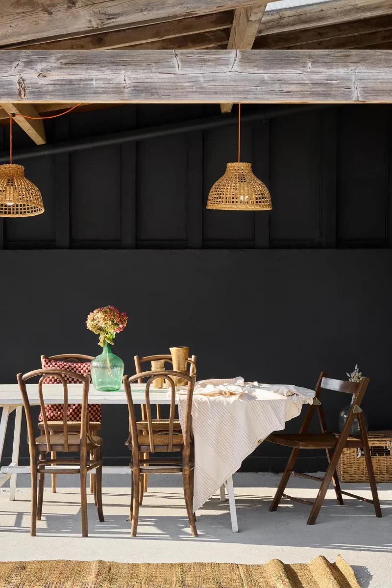 Salle à manger chaleureuse avec charpente apparente en bois sombre et grande table de repas.