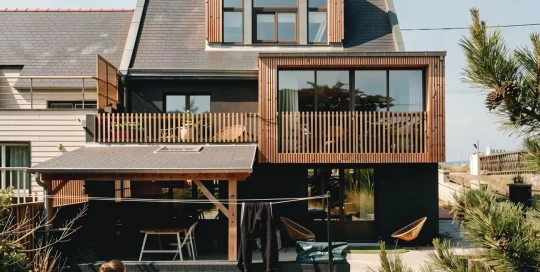 Façade arrière de la maison montrant la surélévation moderne en bois et l'extension à Batz-sur-Mer.