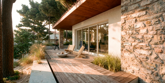 Terrasse-loggia de la villa classée, mur en granit rose et large débord de toiture bois, pinède de La Baule