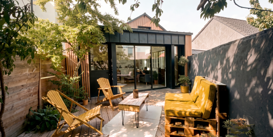 Extension contemporaine en zinc pré-patiné noir et bardage bois à claire-voie d'une maison de ville à Guérande, vue depuis la terrasse