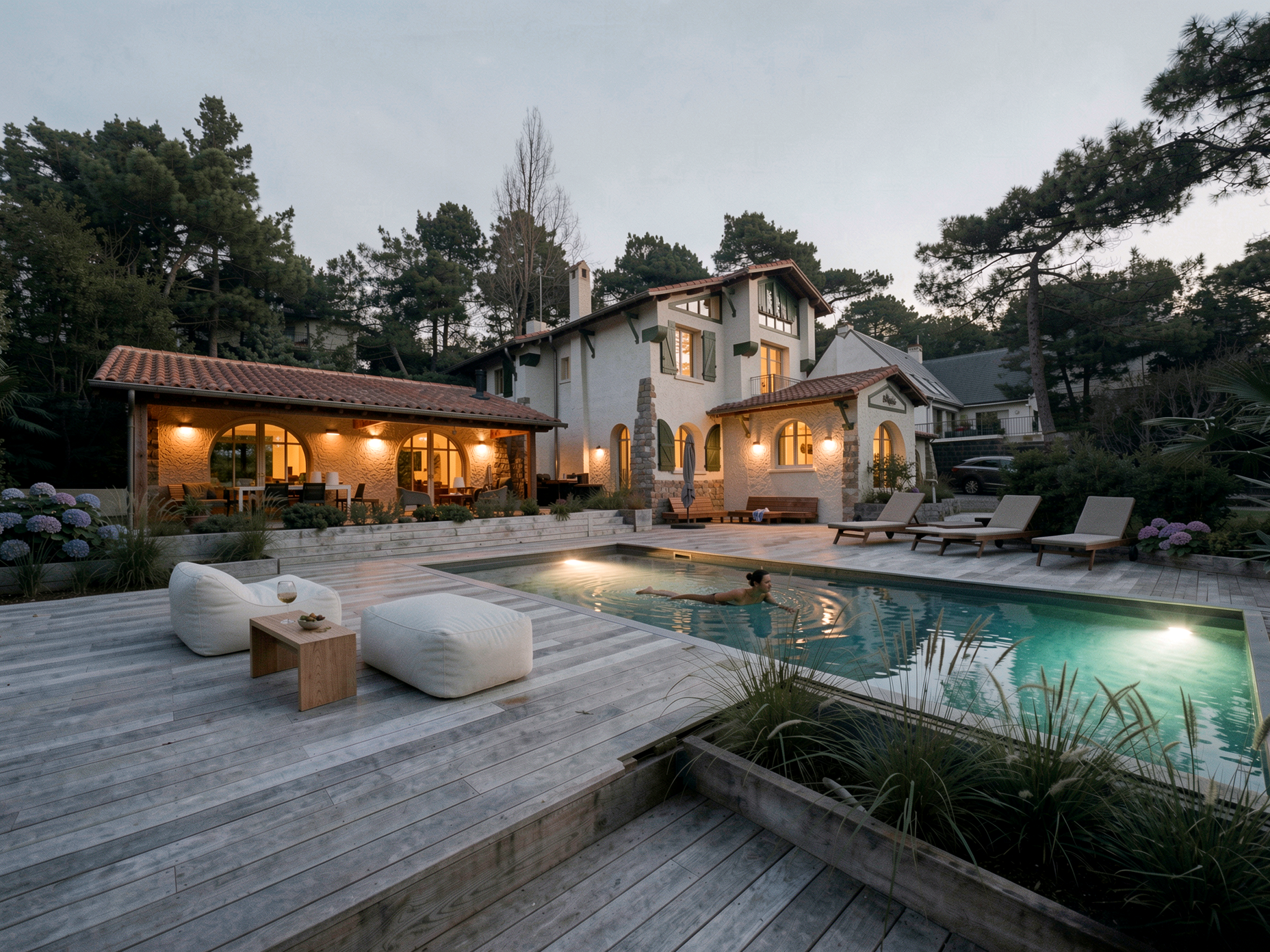 Piscine et terrasse de la villa basque au crépuscule, extension éclairée ouverte sur le jardin, La Baule