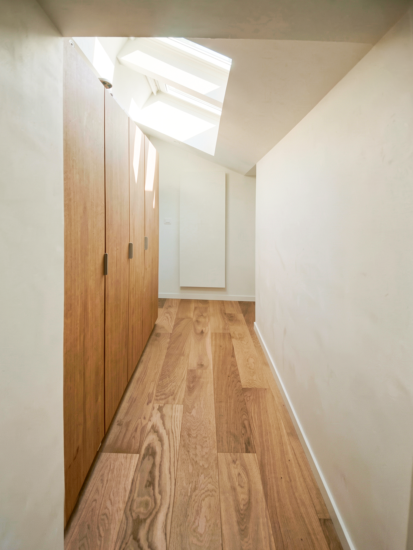 Couloir sans ressaut bordé de rangements en chêne toute hauteur, adapté à la mobilité réduite